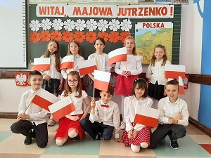 Na zdjęciu znajdują się uczniowie klasy II, trzymający w rękach flagi Polski