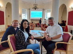 Na zdjęciu znajduje się trzech nauczycieli języka angielskiego, a z tyłu za nimi rozmawia dwoje ludzi