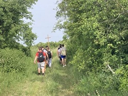 Na zdjęciu znajdują się uczniowie klas VII i VIII niosący krzyż. Wszyscy od odwróceni tyłem